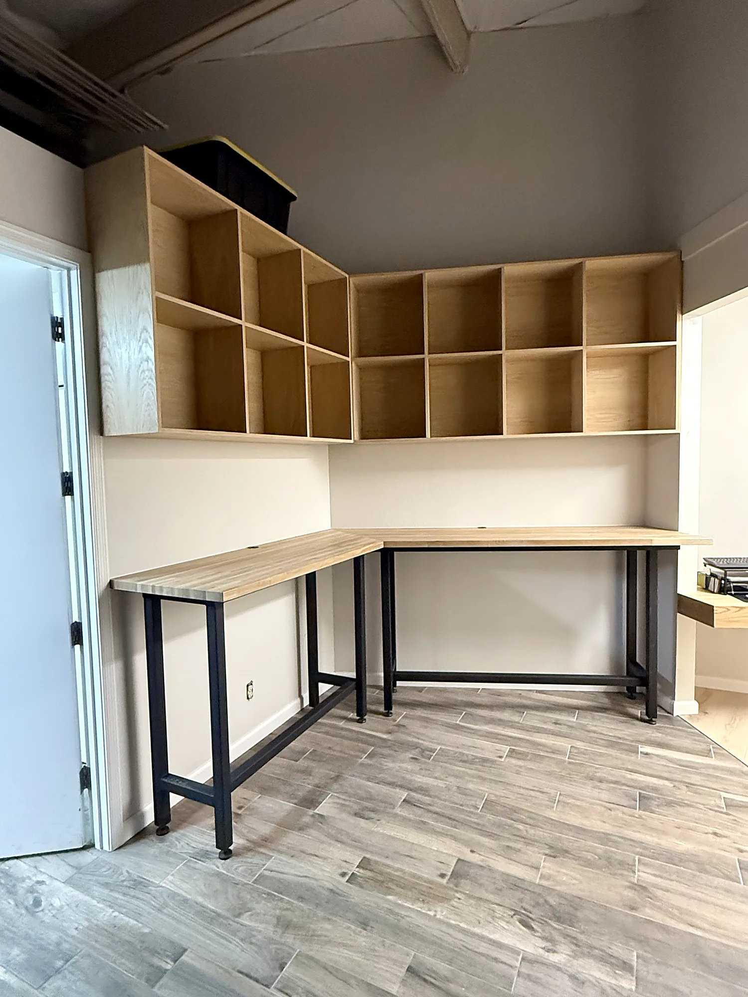 White oak cubbies over an L-shaped butcher block work bar on a matte black steel frame